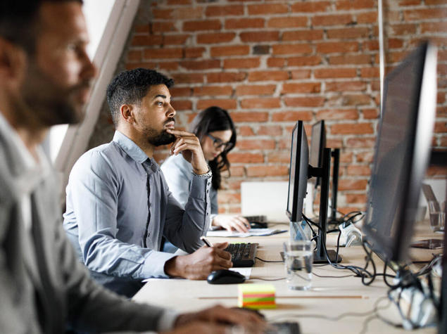 a group of people sitting at a desk looking at computers