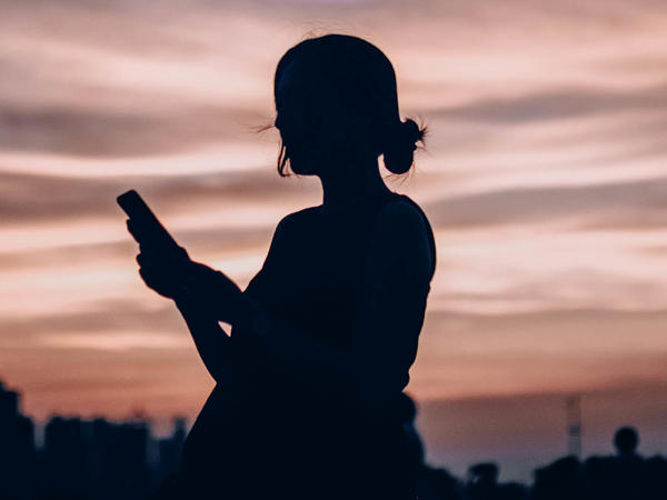 a silhouette of a woman holding a phone