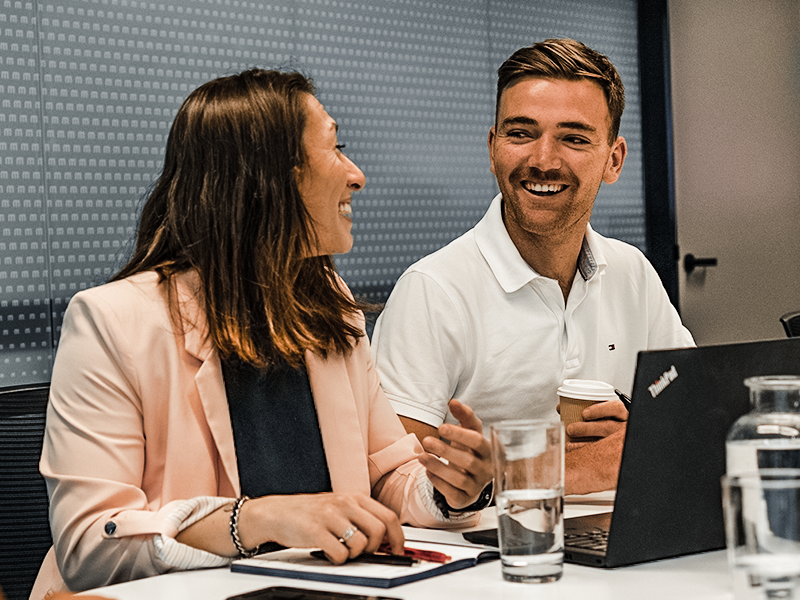 a man and woman sitting at a table with a laptop