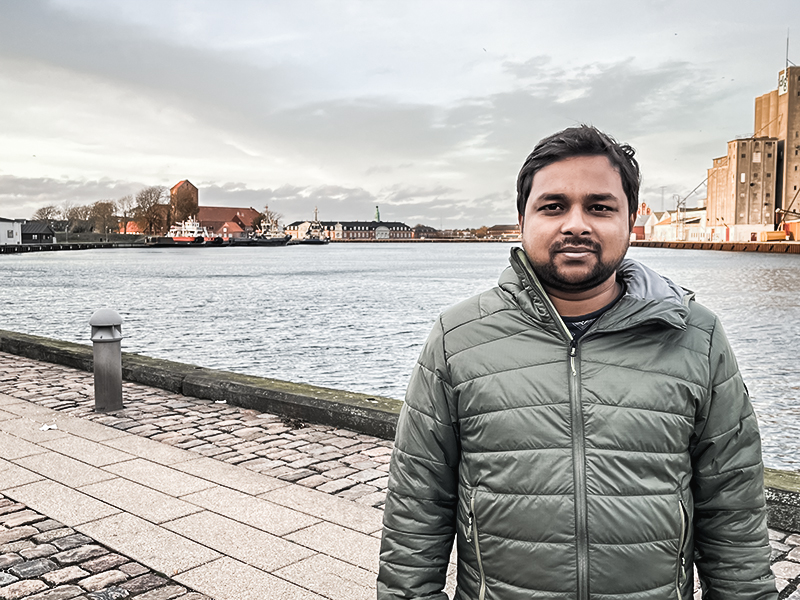a man standing on a sidewalk next to water