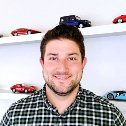 a man smiling in front of a shelf with toy cars