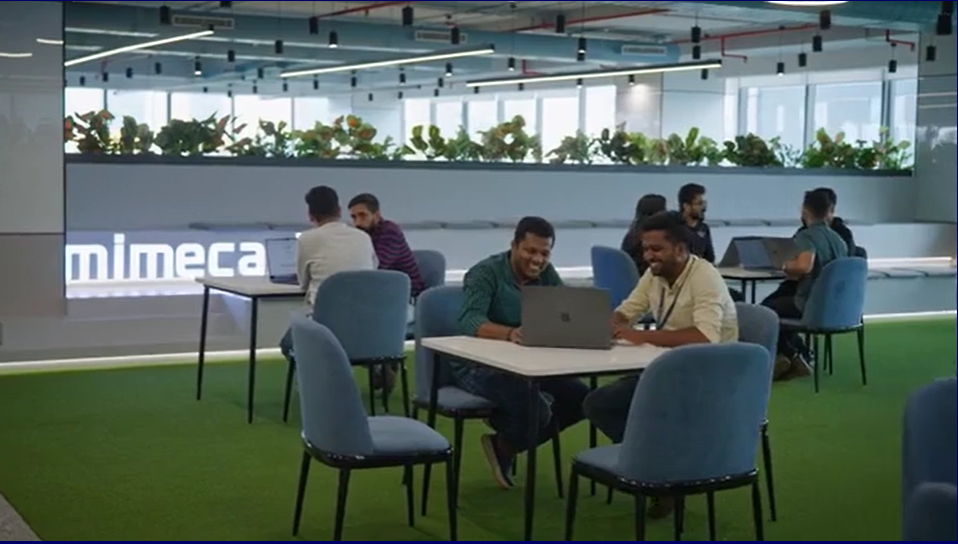 a group of people sitting around a table with laptops